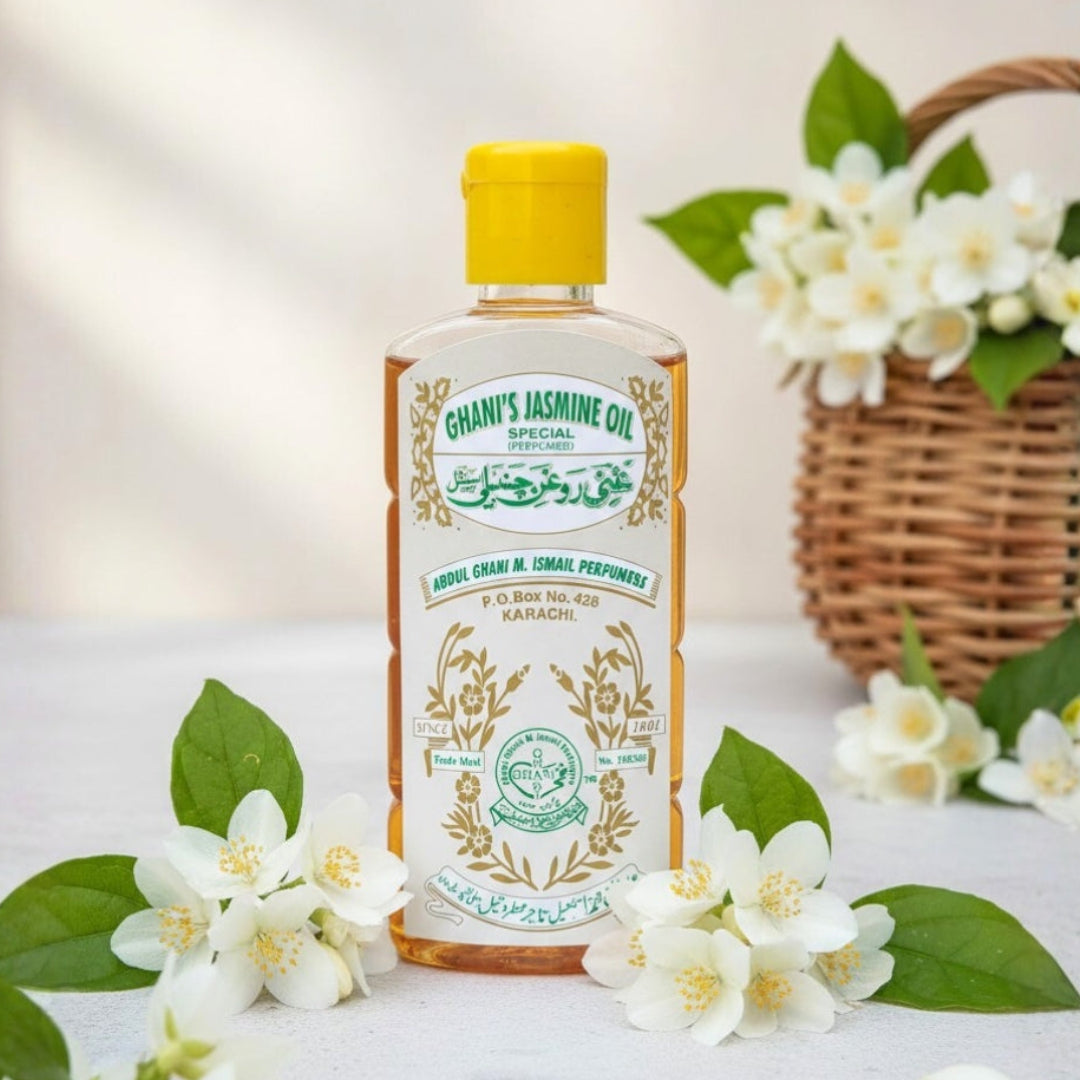 Bottle of Ghani's Jasmine Oil with jasmine flowers on a light background