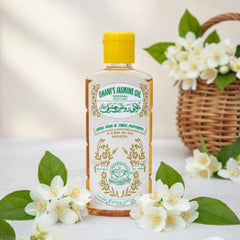 Bottle of Ghani's Jasmine Oil with jasmine flowers on a light background